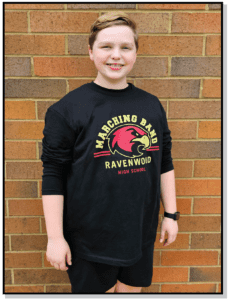 A boy standing in front of a brick wall.