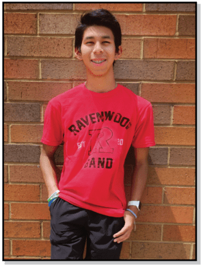 A young man standing in front of a brick wall.