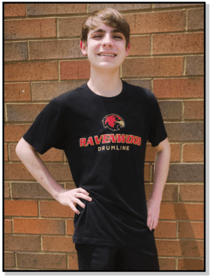 A boy in black shirt standing next to brick wall.