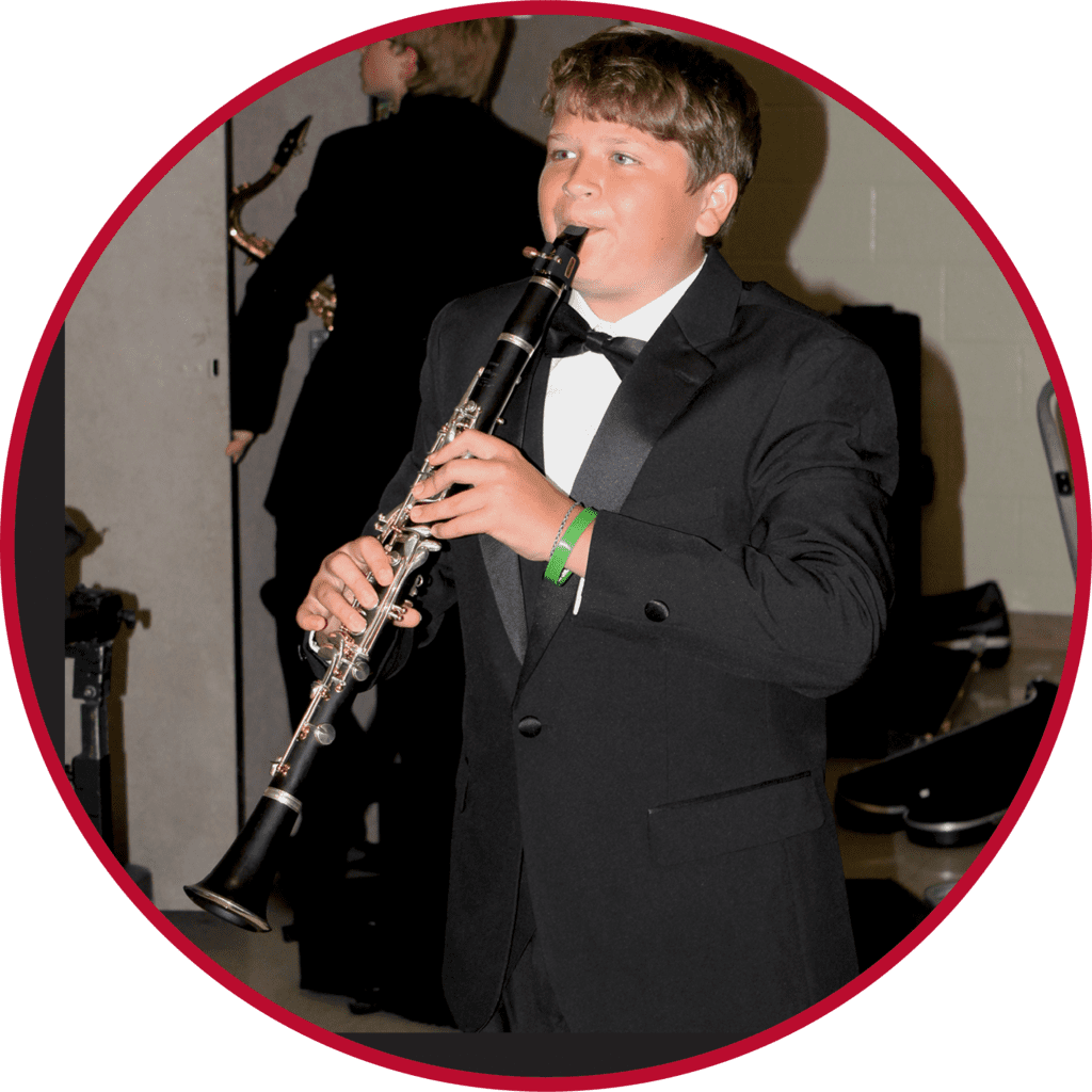 A boy in a tuxedo playing the clarinet.