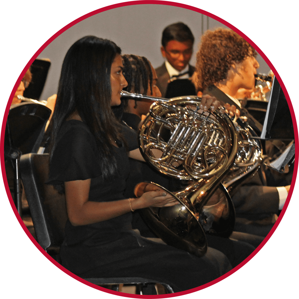 A woman holding a french horn in front of other people.